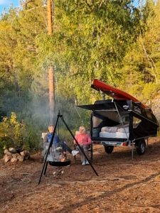 Par slapper av ved bål, ved sin Norwegian Camper.