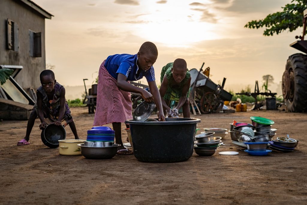 Children in Togo village wash dishes outside