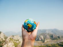 person holding world globe facing mountain