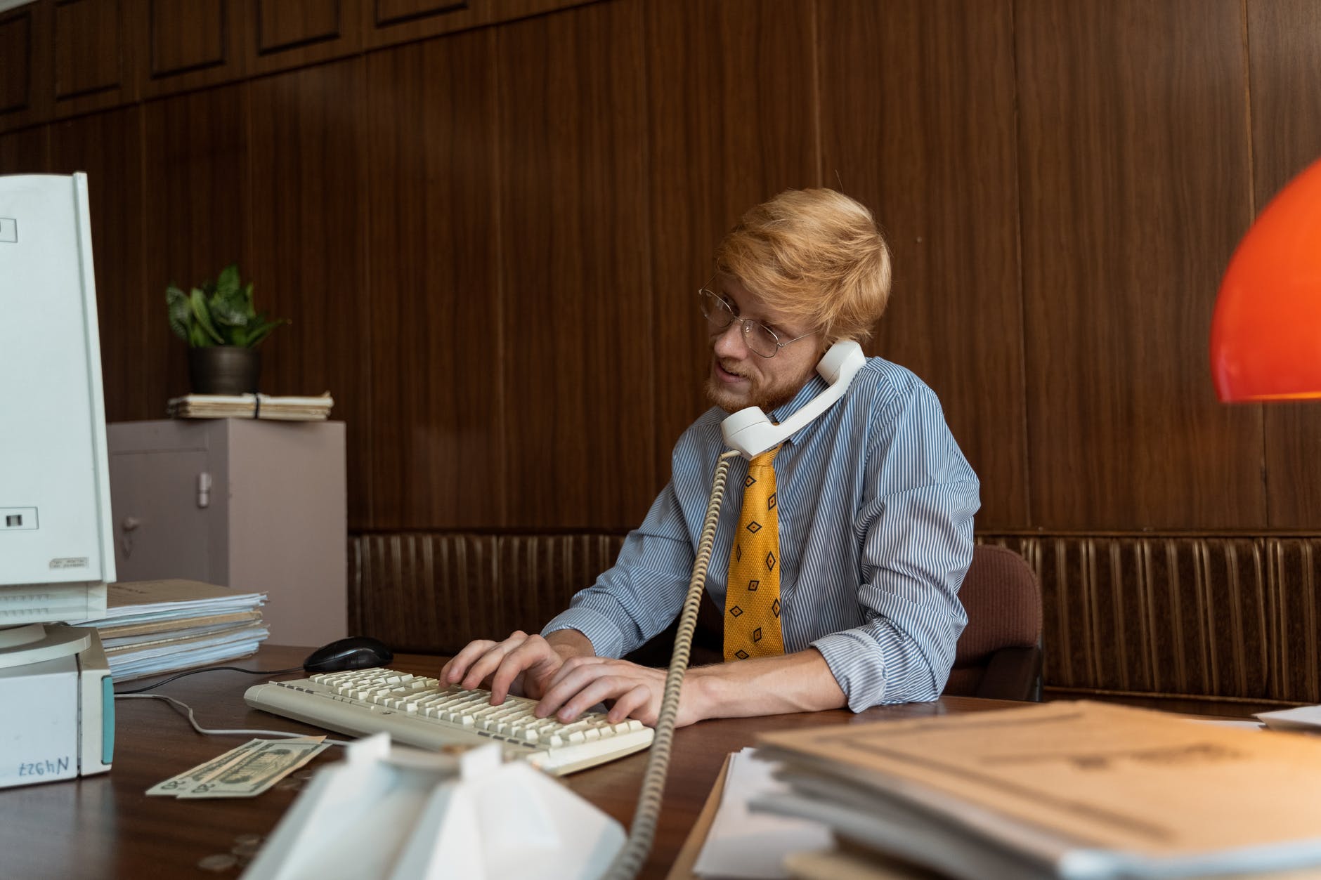 a businessman typing on laptop while on a phone call