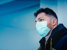 man in black and yellow jacket with face mask