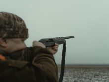 photograph of a hunter using a black shotgun