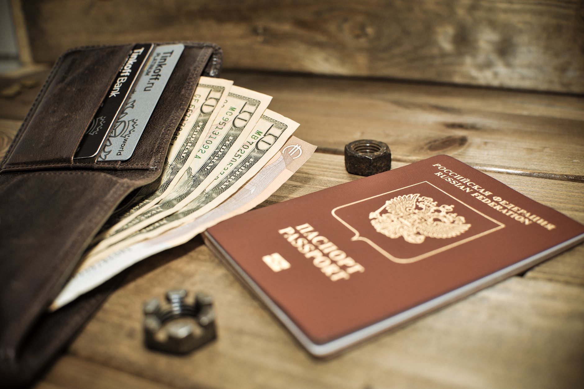 photo of a brown passport beside a wallet with dollar bills