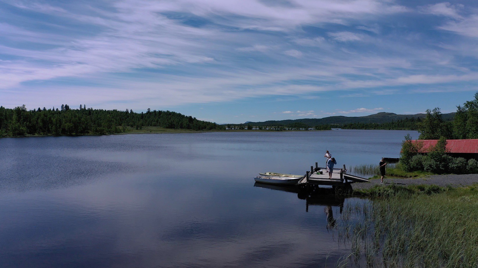 Utsikt over Røssjøen naturreservat i Valdres – speilblank innsjø omgitt av fjell og skog.