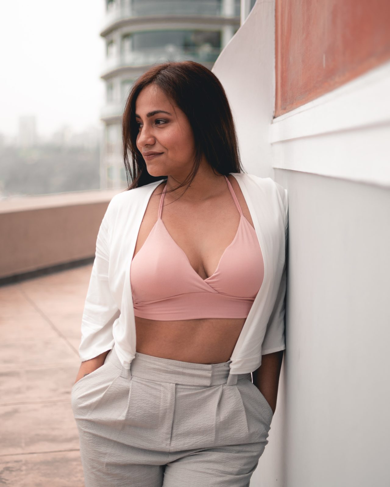 Femme portant un soutien-gorge bralette rose pâle avec une tenue chic et estivale.