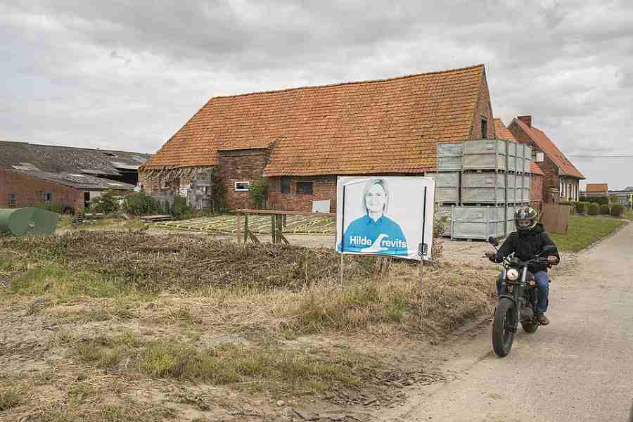 Aan een boerderij hangt een vergeelde affiche van een lijkbleke Hilde Crevits. “Verschoten van de uitslag.” © Sebastian Steveniers