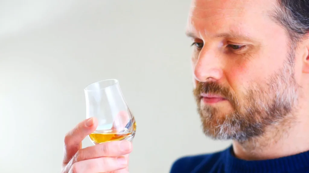 Man looking at a glass of whisky before tasting 