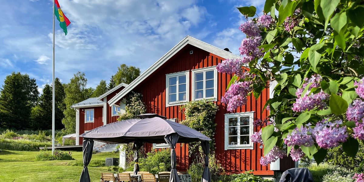 Gårdshuset med uteplats i södeläge. På vänster sida står flaggstången med Nordingråflaggan och boningshuset i bakgrunden.