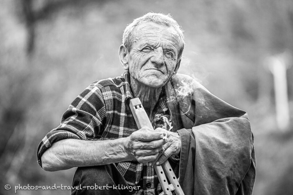 A farmer in Albania with a traditional flute, Every man is smoking in Albania