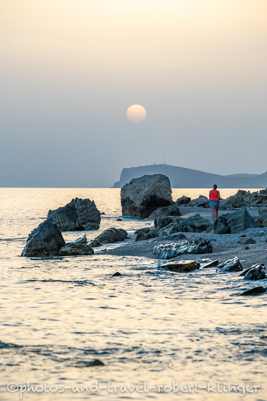 A woman walking along the beach in Albania during sunset