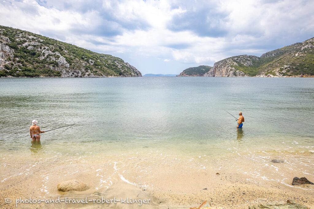 A man and a woman fishing on a beach in Greece