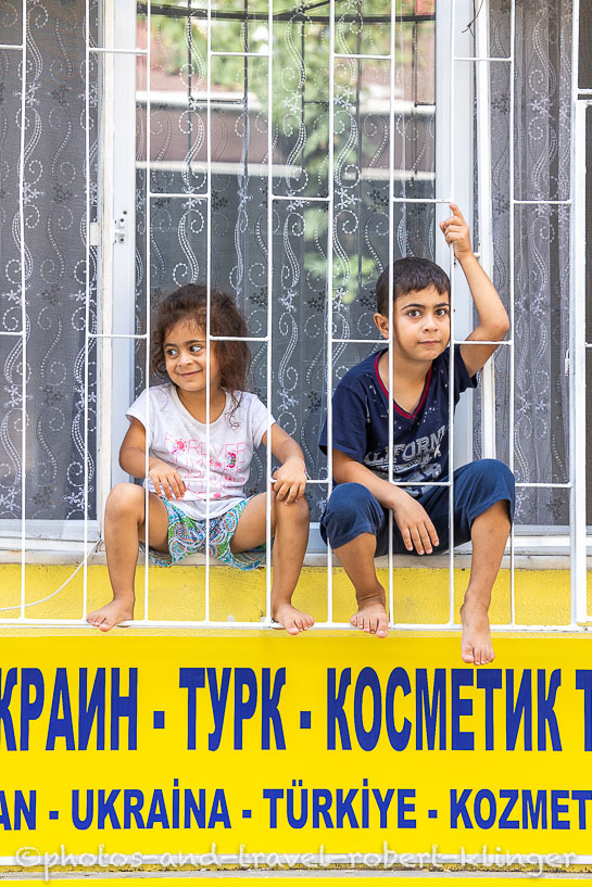 A boy and a girl sitting behind a grid on a window in Istanbul
