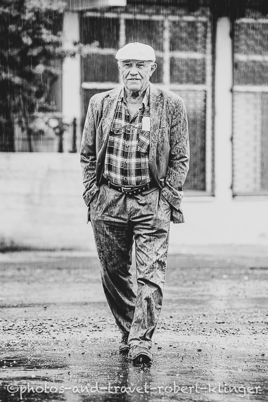 Black and white photo of a turkish man crossing the road in the rain