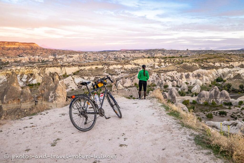 A woman resting with her bycicle in Cappadocia during sunset