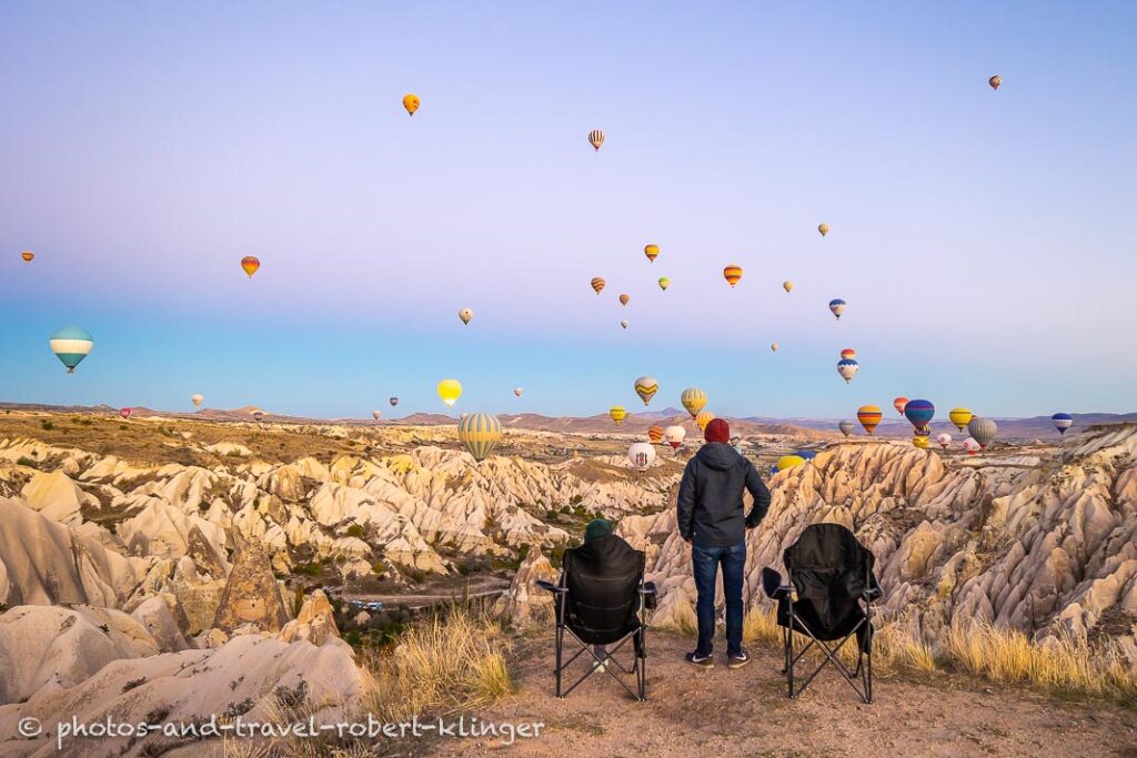 A couple watching the many hot air ballons in Cappadocia before sunrise