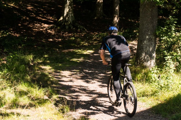 En man på Mountainbike, på väg in i skogen.