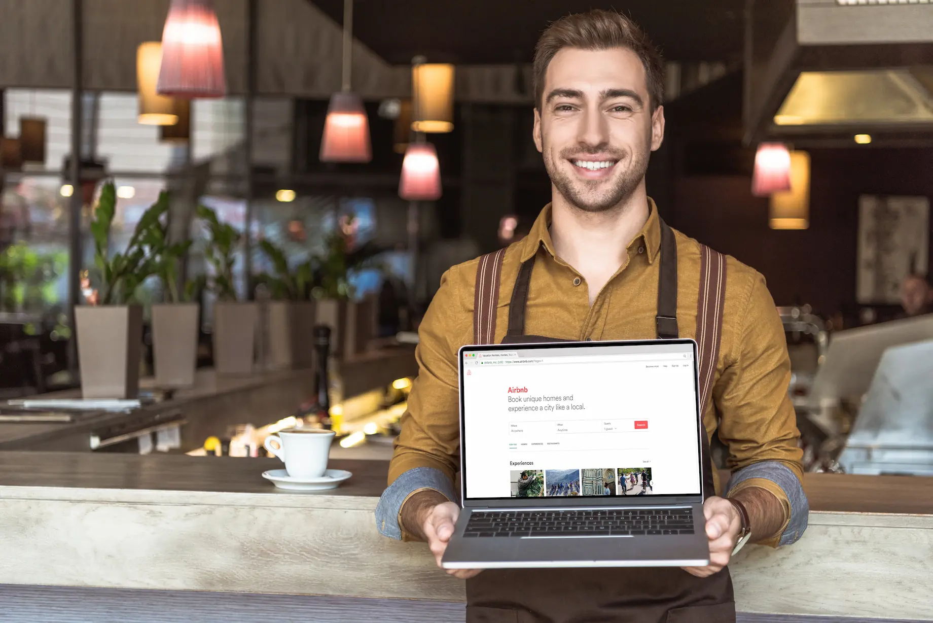 handsome-young-waiter-holding-laptop-with-airbnb-w-2023-11-27-05-00-03-utc