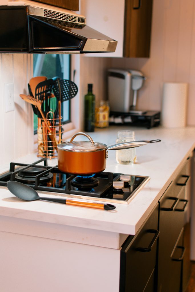 A pot on the stove in a tiny kitchen.