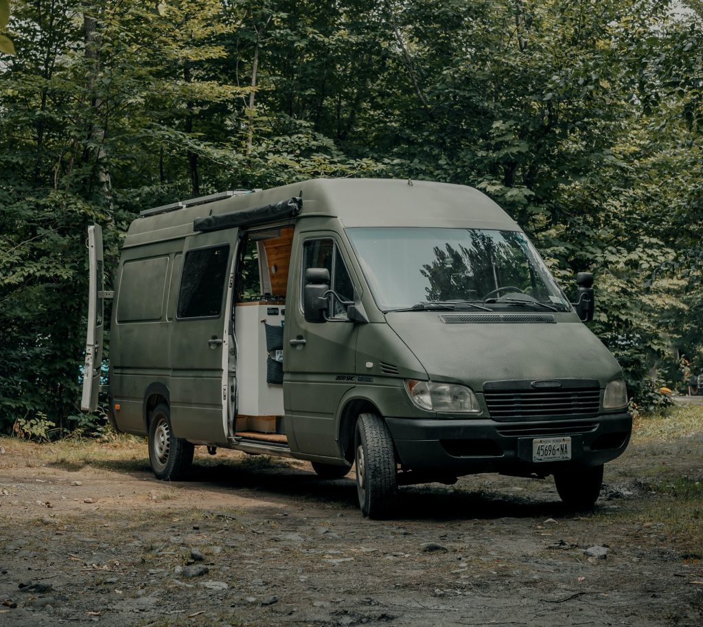 A van parked in the forrest.