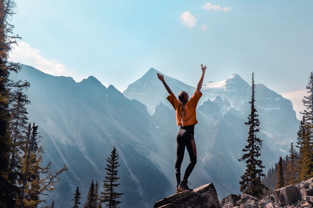 Woman standing on a rock with arms up enjoying fresh air
