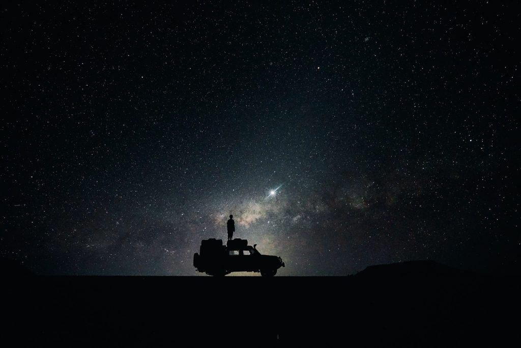 Ella on top of her campervan under the night sky