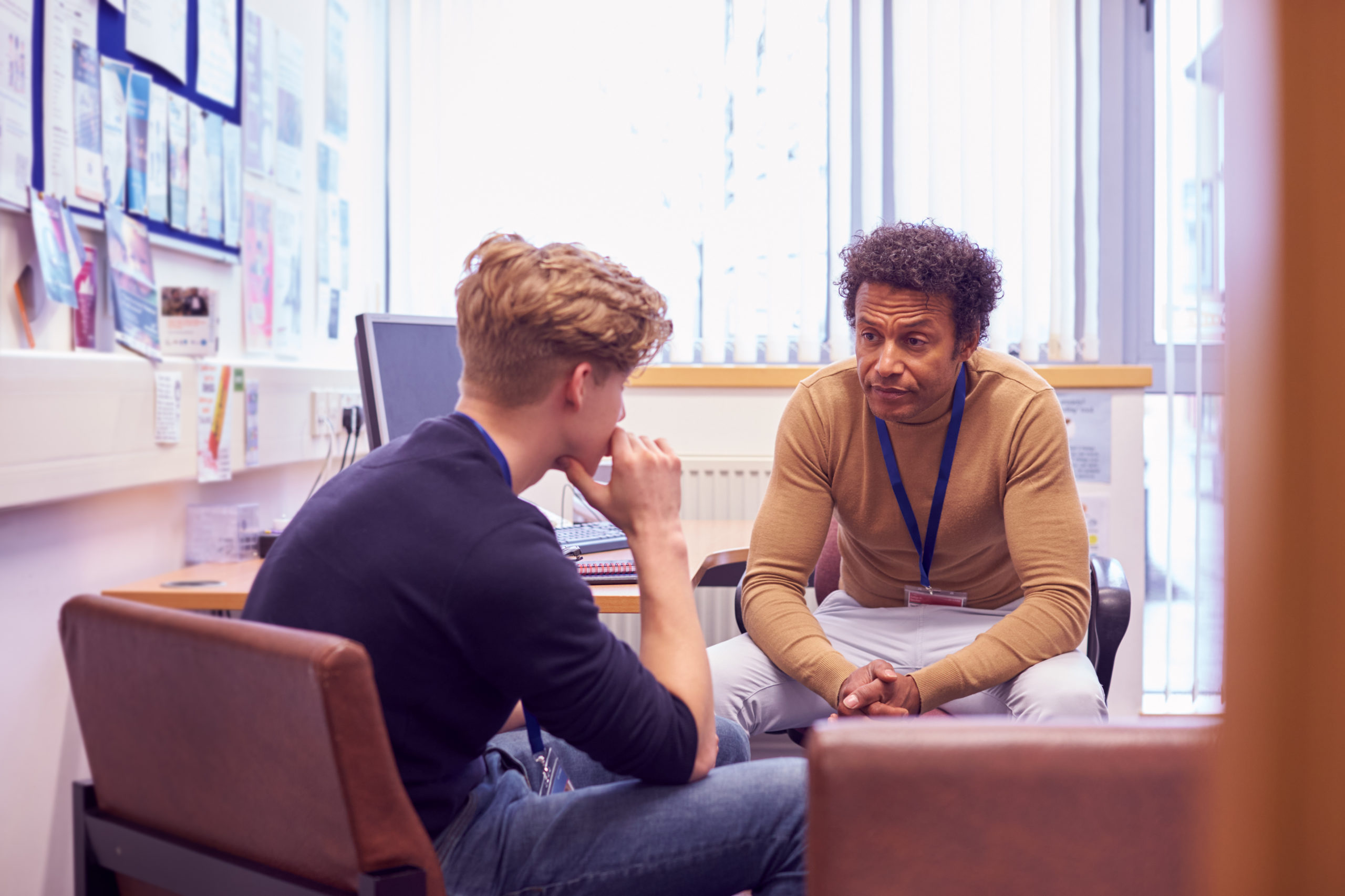 Male College Student Meeting With Campus Counselor Discussing Mental Health Issues