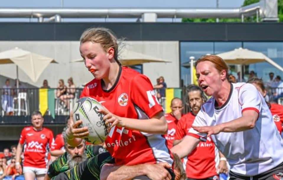 MIXAR-speelster van Rugby Club Diabolos Schilde in actie tijdens een wedstrijd, terwijl ze een tackle ontwijkt met de bal in handen.