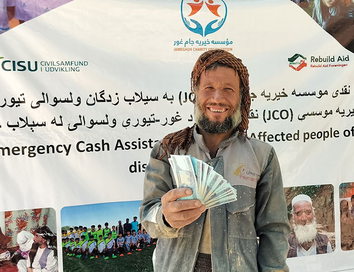 Flood-affected community member holds received cash assistance during an emergency response implemented by Saifrood Unity and Aid Organization with support from Rebuild Aid Forening in Ghor Province, Afghanistan.