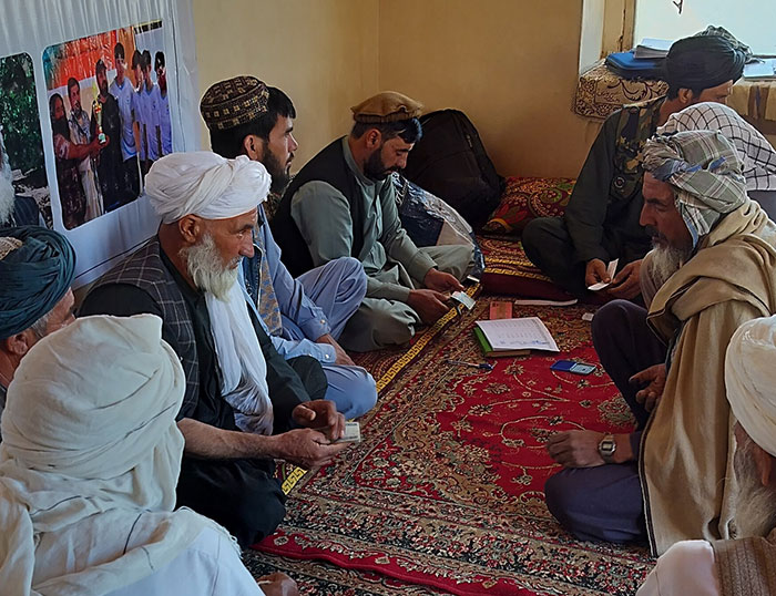 Flood-affected community members and local elders sit indoors during a verification and consultation session conducted by Saifrood Unity and Aid Organization with support from Rebuild Aid Forening as part of an emergency flood response in Ghor Province, Afghanistan.