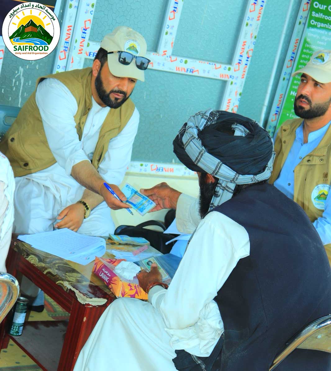 Project staff handing emergency cash assistance to a verified beneficiary in Khost Province.
