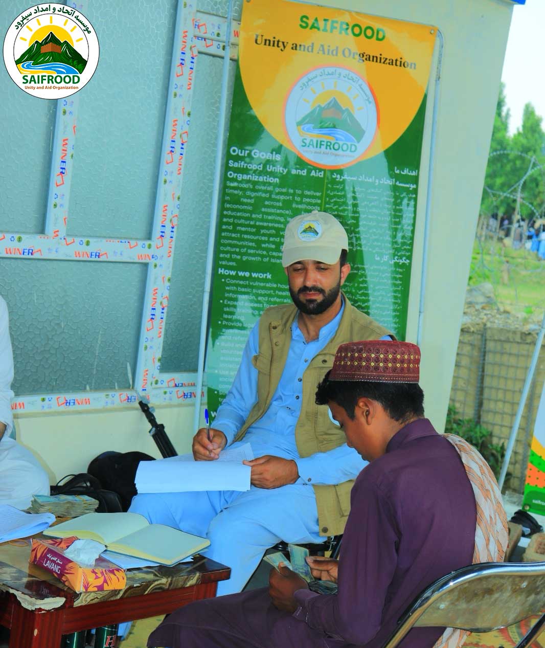 Project staff registering a beneficiary before emergency cash assistance distribution in Afghanistan.