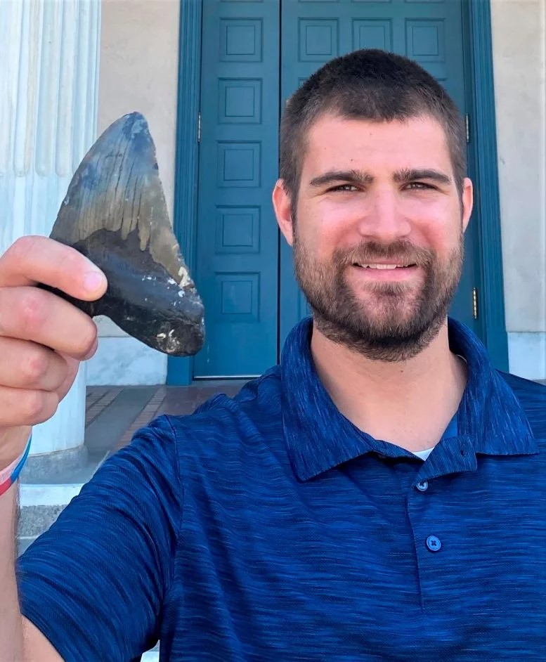 Phillip Sternes, biologo della UC Riverside e primo autore dell'articolo, tiene in mano un dente di Megalodonte. Crediti: Douglas Long/Accademia delle Scienze della California
