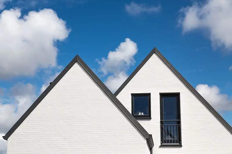 Udsigt over et hvidt hus med sorte tagsten.