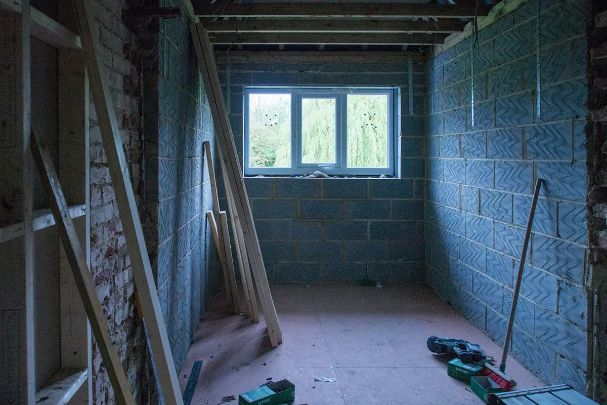 Ufærdigt rum med synlige mursten og træplader under renovering.