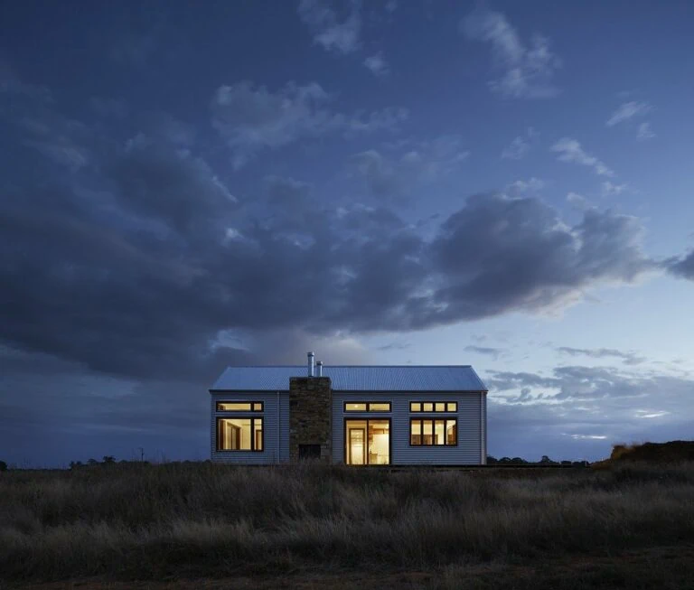 An off-grid home lit up in the middle of a field of grass