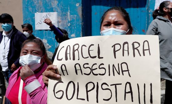 Bolivian people hold up placard 'Prison for the murderer coup-maker!!!'