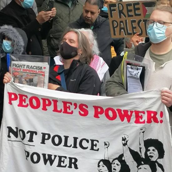 Nottingham comrades hold a banner in a crowd reading 'People's power not police power'
