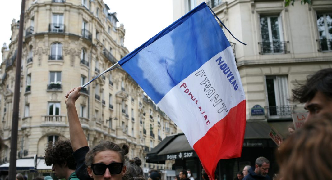 A man waves a tricolour flag with the words 'Noveau Front Populaire'