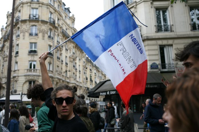 A man waves a tricolour flag with the words 'Noveau Front Populaire'