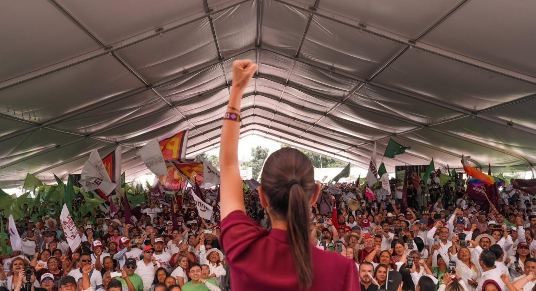 Claudia Sheinbaum raises a fist in front of an audience of MORENA supporters