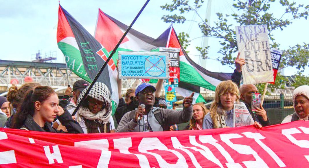 Protesters march under Palestine flags behind a banner reading 'Isolate the Zionist state'