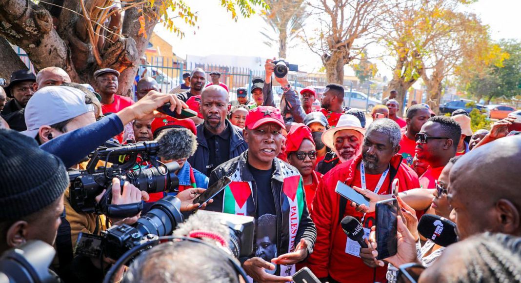 Julius Malema of the EFF speaks to a crowd of supporters and journalists with a Palestine-themed scarf draped over his shoulders