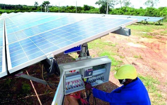 A Cuban workman in a hard hat examines a solar energy array. (Photo: Periódico Ahora)