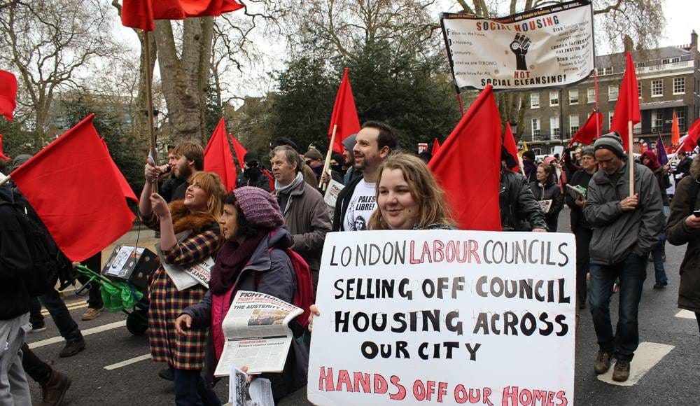 Archive photo: Activist holding a placard that reads 'London Labour Councils selling off council housing across our city - Hands off our Homes.