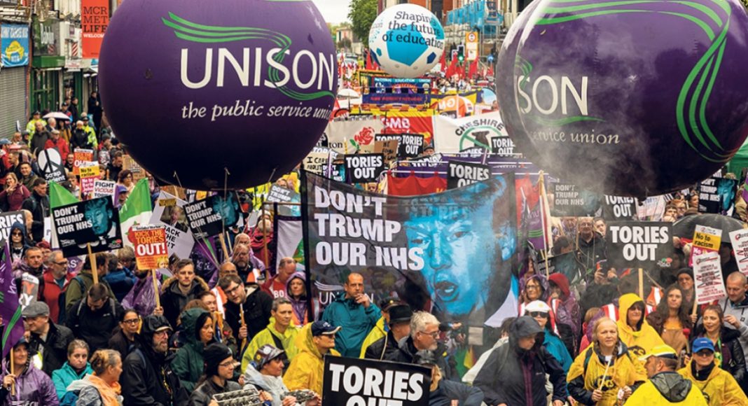 Trade unions march with banners in Manchester. Placards read 'Tories out'