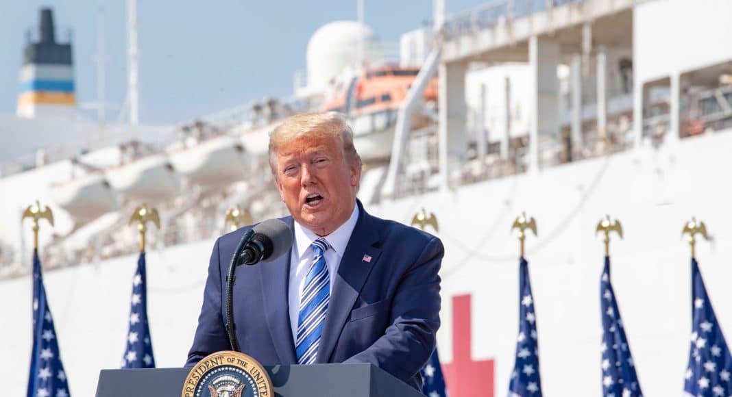 US President Donal Trump delivered a speech in front of a row of US flags and a naval ship in the background