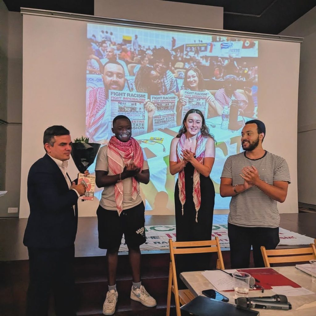 Solidarity with Cuba meeting at Bolivar Hall, 16 July 2025. Brigade members applaud as Pablo Ginarte accepts a gift of flowers
