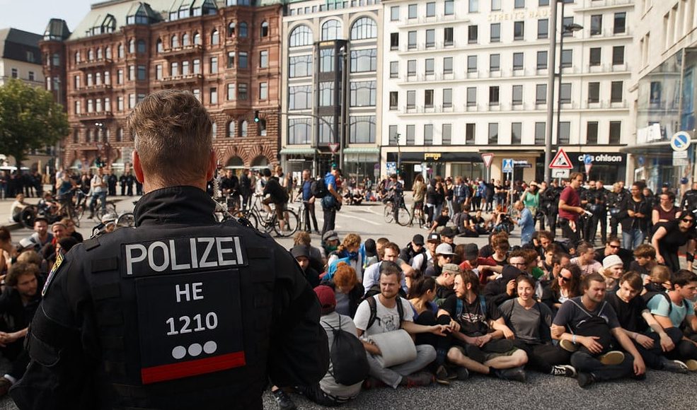 A German police officer observes a crowd of protesters