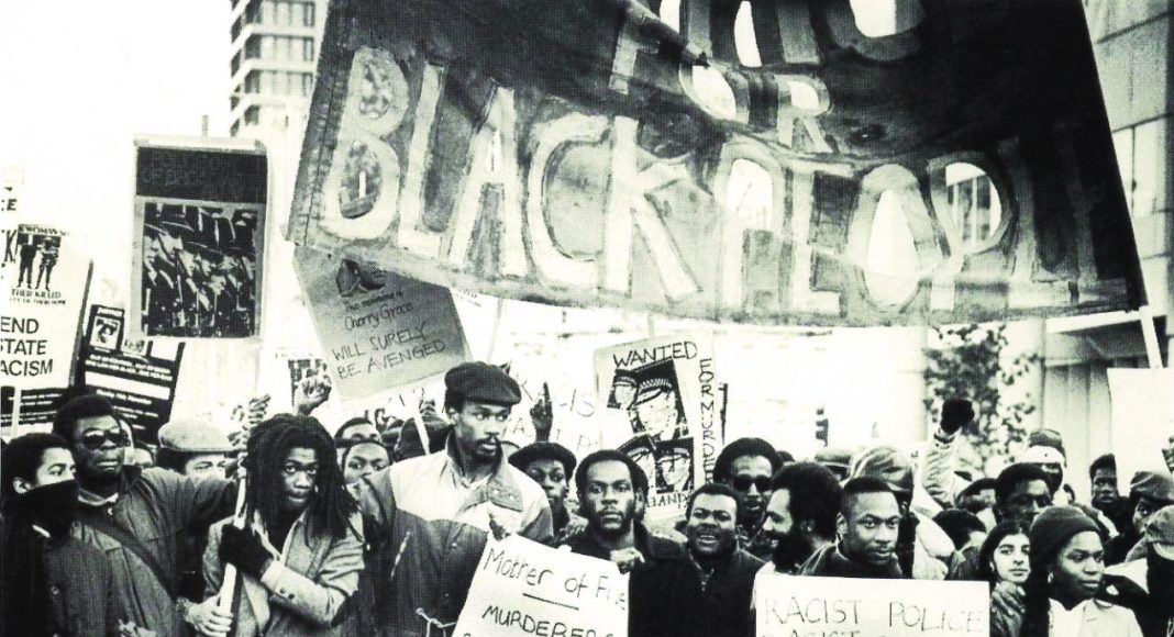 Black protesters march under banners, demand an end to state racism, black and white photograph