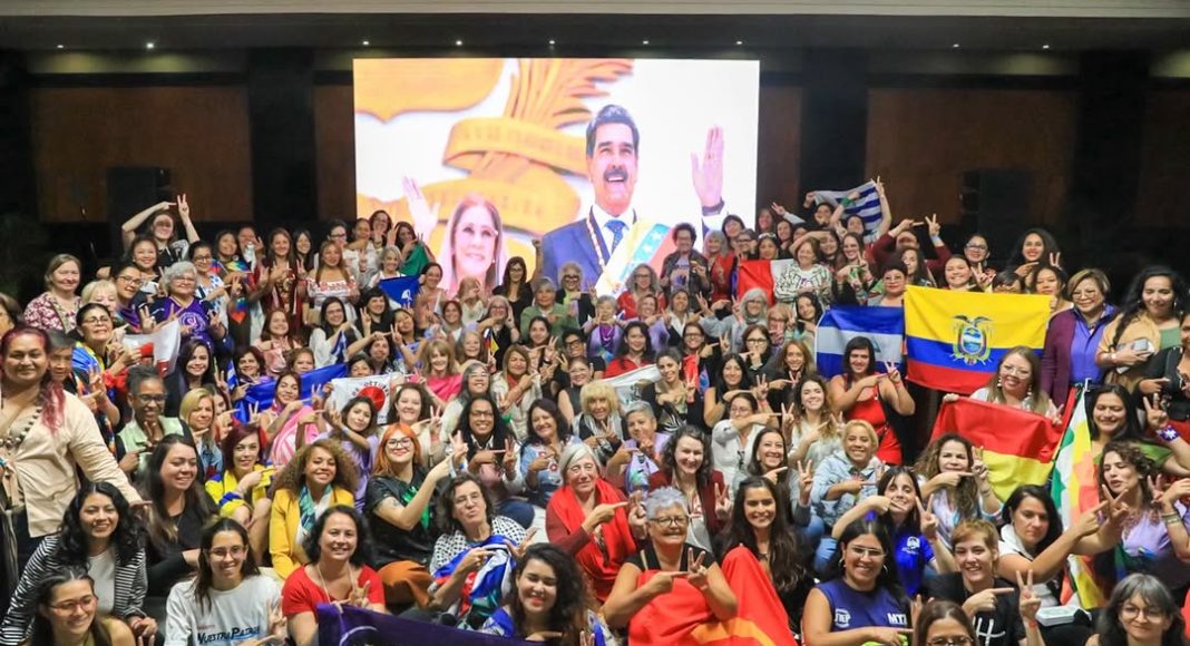 Cilia Flores International Women’s Brigade in Caracas, Venezuela. A large group of women holding flags and banners pose in front of an image of Nicolas Maduro and Cilia Flores (photo: PSUV)